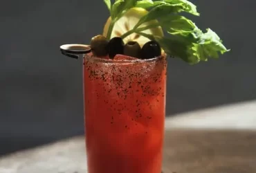 Prikaz Bloody Mary koktela koji je ukrašen stabljikom celera, maslinom i kriškom limuna.