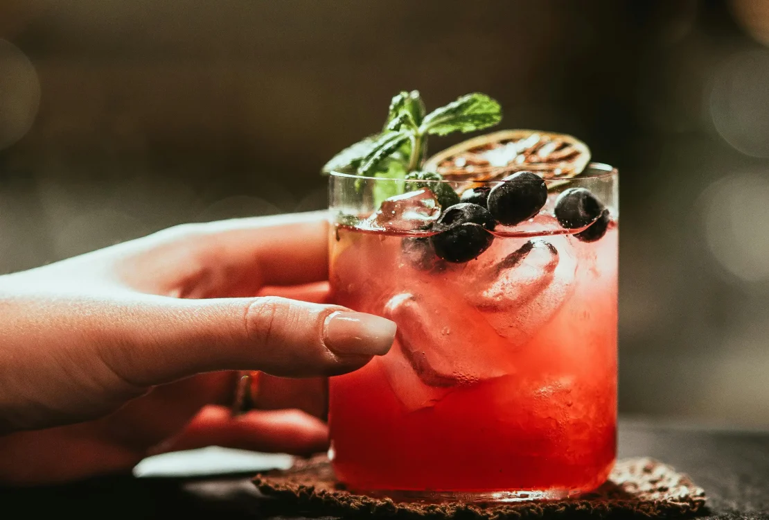 Bramble koktel crvenkaste boje, ukrašen kupinama i kolutom limuna.1