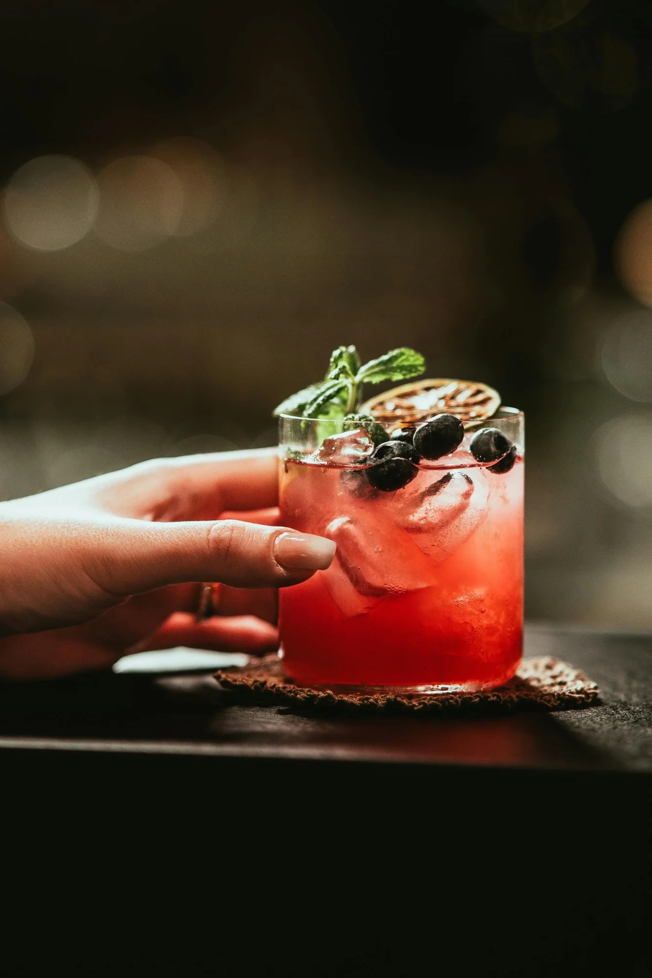 Bramble koktel crvenkaste boje, ukrašen kupinama i kolutom limuna.1